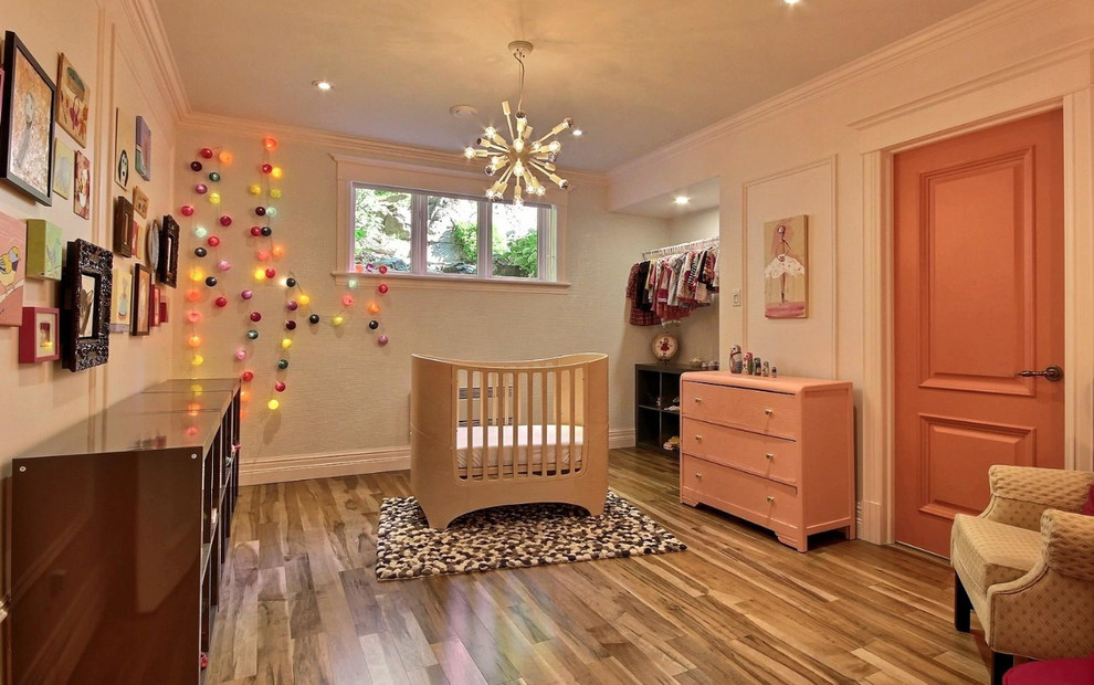 Idée de décoration pour une chambre de bébé fille design de taille moyenne avec un mur blanc, un sol en bois brun et un sol marron.