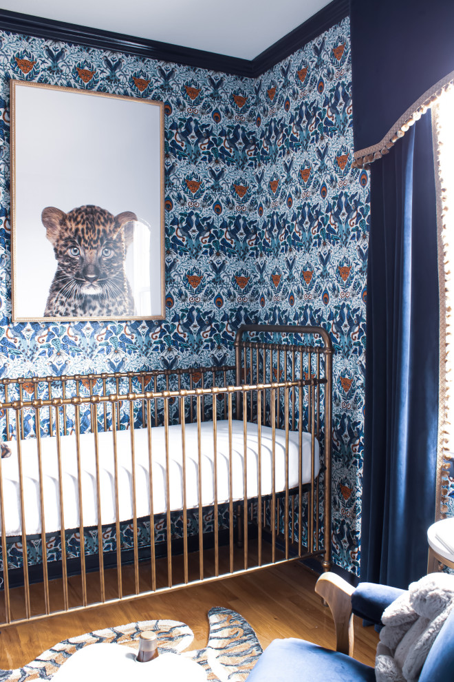 Cette photo montre une chambre de bébé garçon éclectique avec un mur bleu, un sol en bois brun et du papier peint.