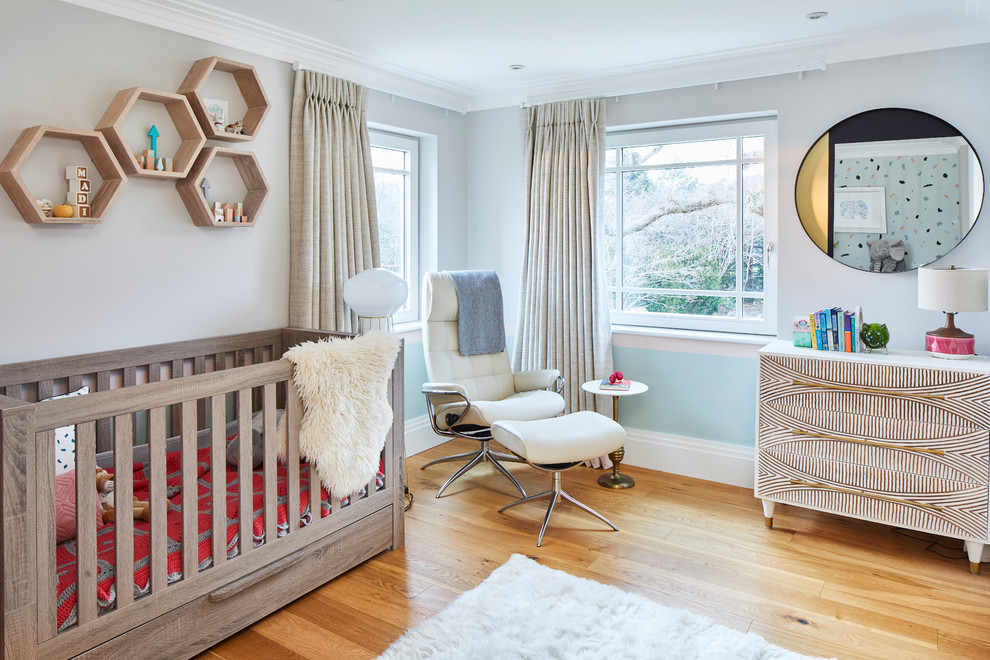 Imagen de habitación de bebé contemporánea grande con paredes azules y suelo de madera en tonos medios