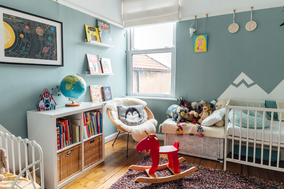 Modelo de habitación de bebé neutra escandinava con paredes azules, suelo de madera clara y suelo marrón