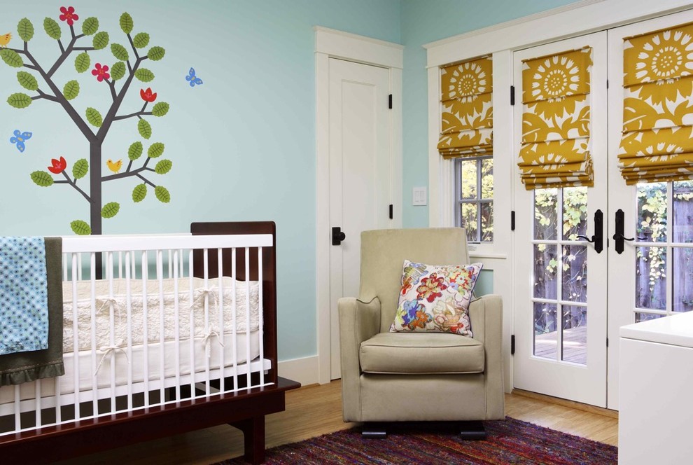 Imagen de habitación de bebé neutra ecléctica con paredes azules y suelo de madera en tonos medios