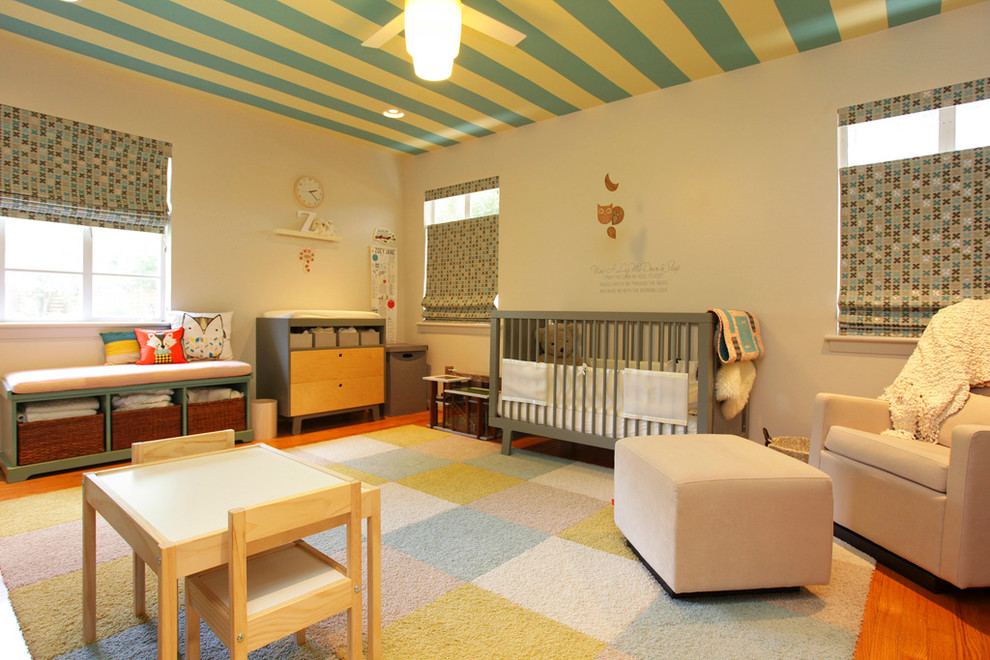 Idée de décoration pour une grande chambre de bébé neutre design avec un mur beige et un sol en bois brun.