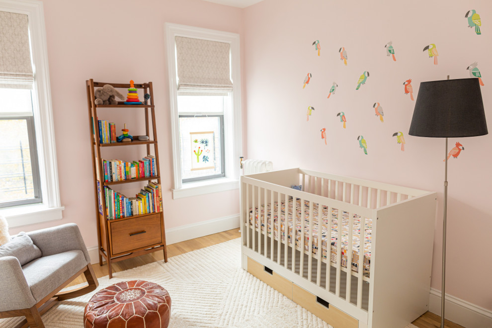 Foto di una cameretta per neonata minimalista di medie dimensioni con pareti rosa, parquet chiaro e pavimento marrone