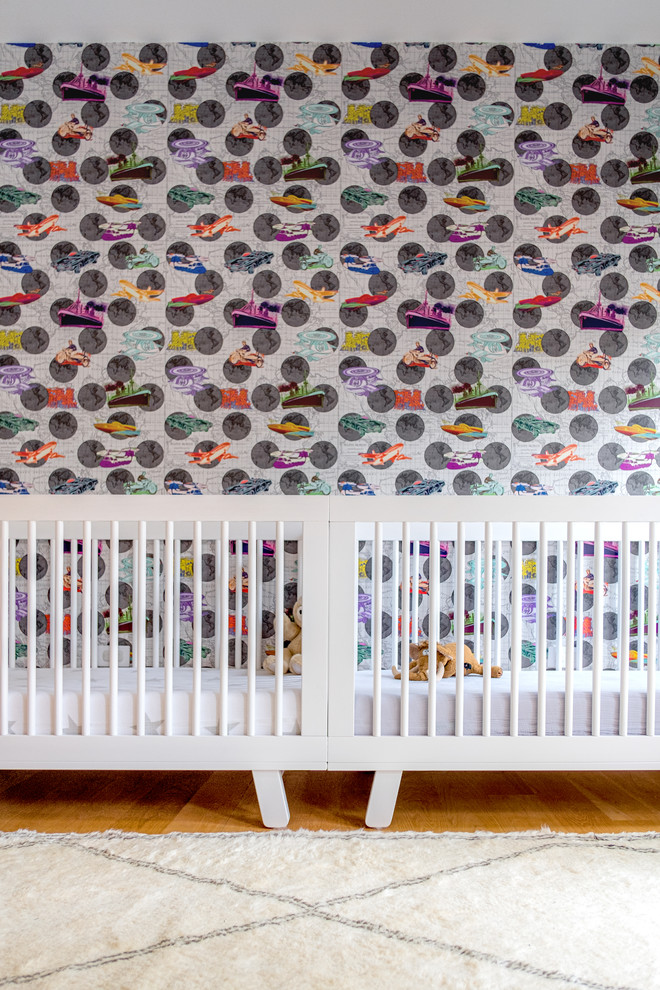 Design ideas for a large modern nursery in New York with multi-coloured walls and light hardwood flooring.