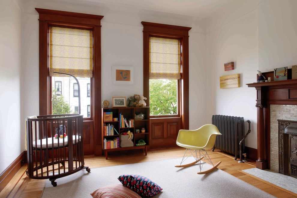 Example of a mid-sized classic gender-neutral medium tone wood floor nursery design in New York with white walls