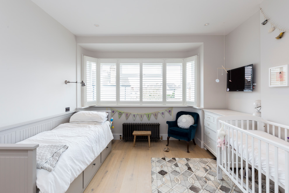 Inspiration for a classic gender neutral nursery in London with white walls, light hardwood flooring and beige floors.