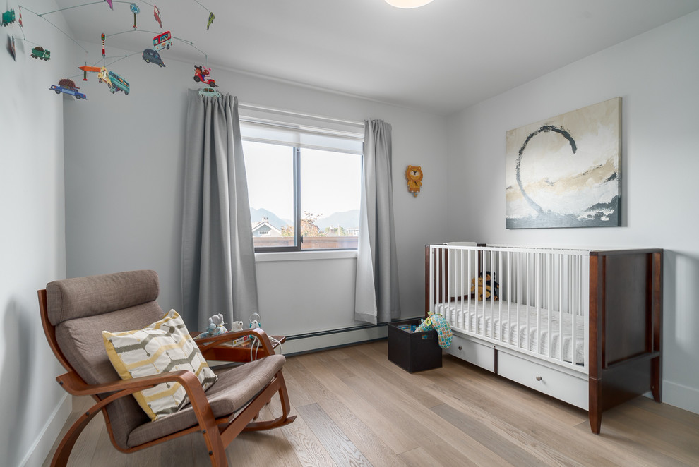 Réalisation d'une chambre de bébé neutre tradition de taille moyenne avec un mur gris, un sol en bois brun et un sol marron.