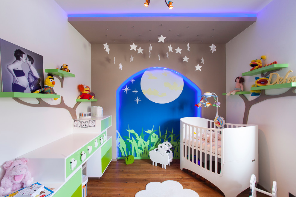 Cette photo montre une chambre de bébé neutre tendance avec un mur gris et un sol en bois brun.