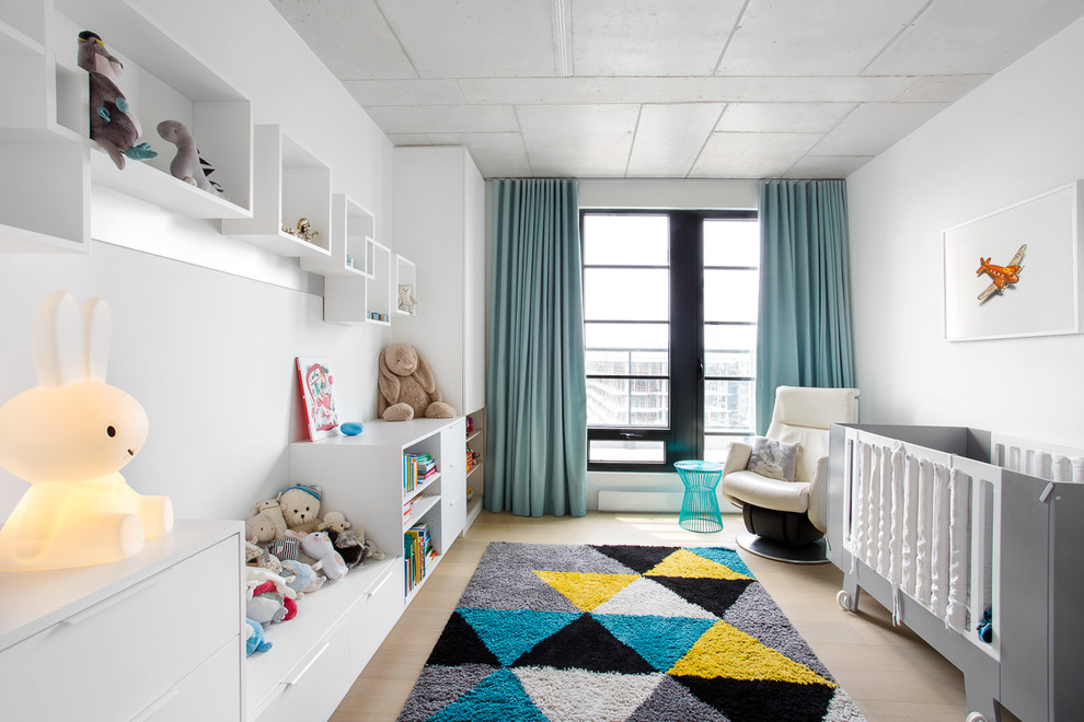 Foto di una cameretta per neonati neutra contemporanea con pareti bianche, pavimento in legno massello medio e pavimento marrone