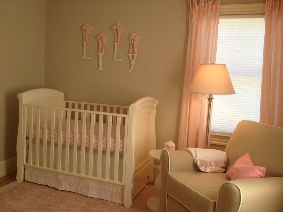 Diseño de habitación de bebé niña tradicional renovada pequeña con paredes beige y suelo de madera oscura