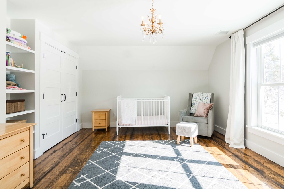 Imagen de habitación de bebé niña campestre grande con paredes blancas, suelo de madera en tonos medios y suelo marrón