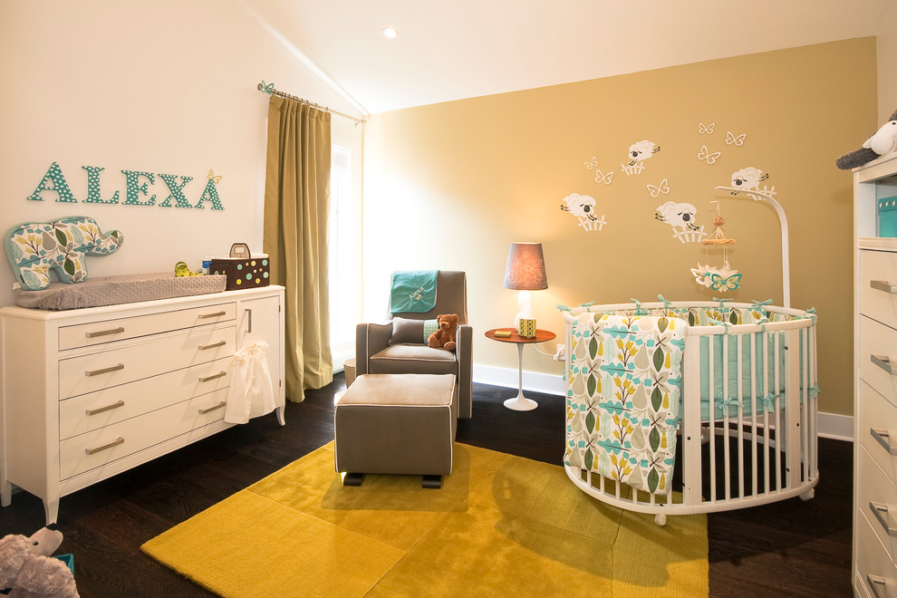 Imagen de habitación de bebé neutra actual con paredes beige y suelo de madera oscura