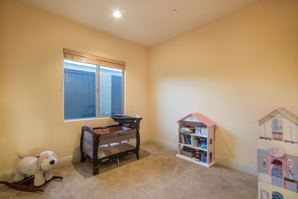 Small mediterranean gender neutral nursery in Los Angeles with beige walls and carpet.