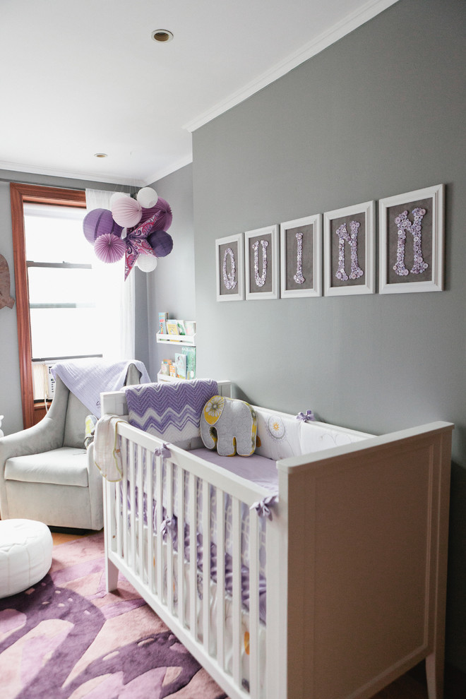 Esempio di una cameretta per neonata bohémian di medie dimensioni con pareti grigie e parquet chiaro