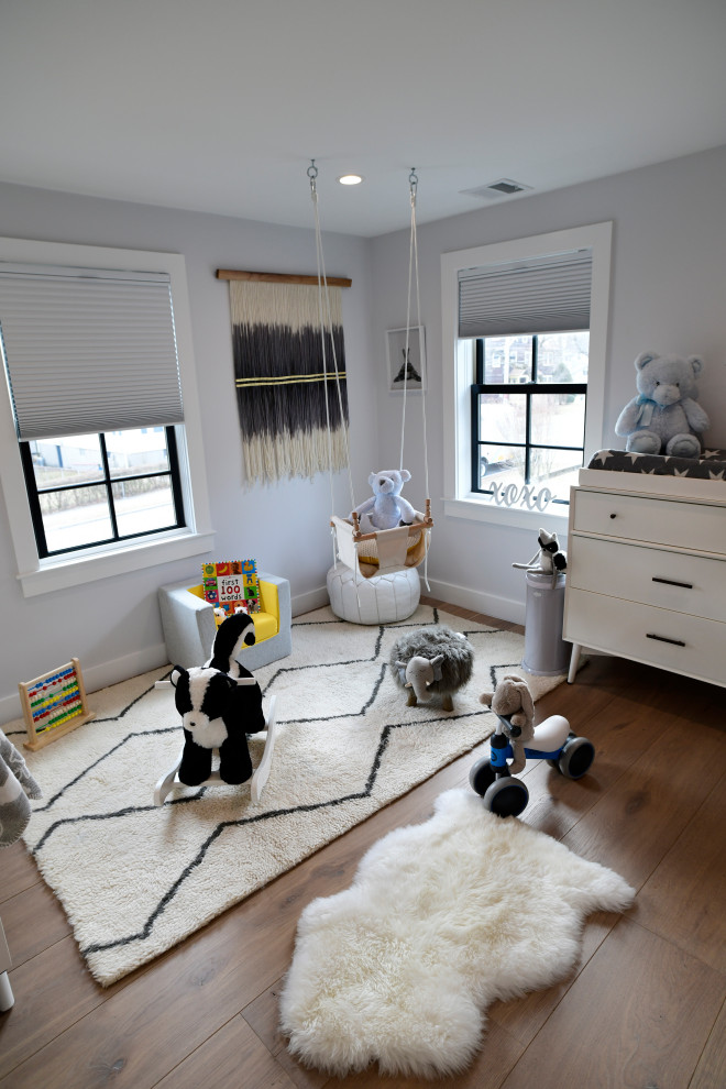 Immagine di una cameretta per neonato moderna di medie dimensioni con pareti bianche e parquet chiaro