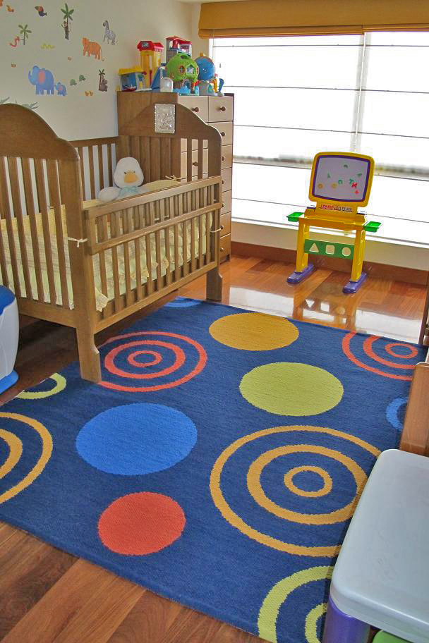Cette image montre une chambre de bébé neutre design de taille moyenne avec un mur beige, un sol en bois brun et un sol marron.