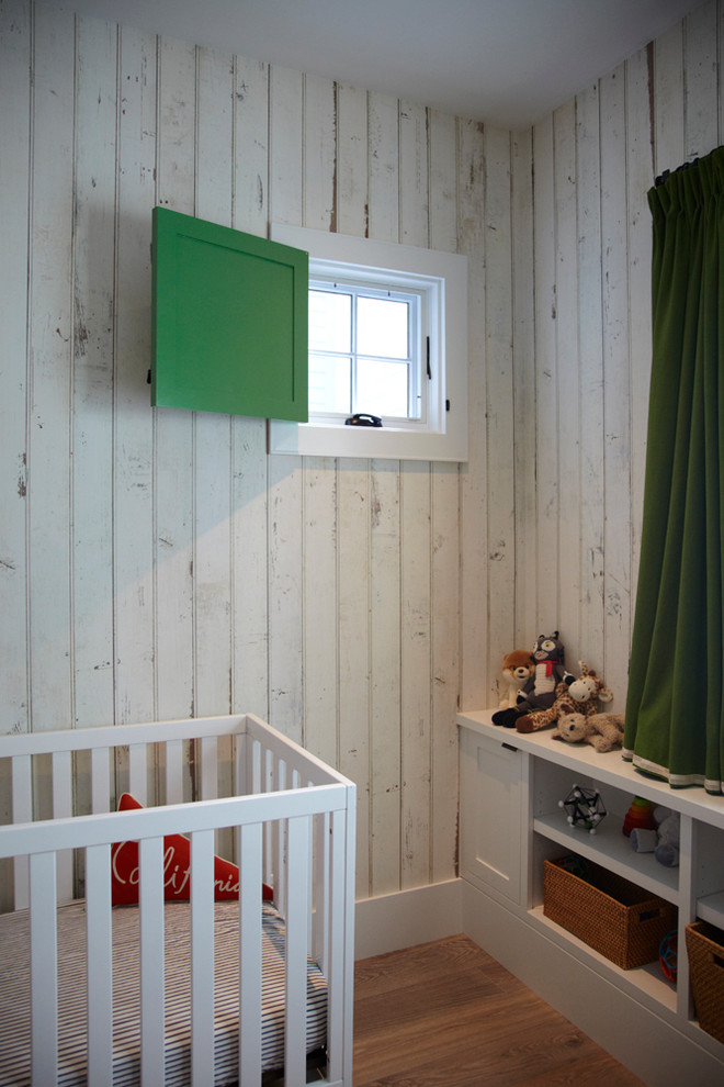 Ejemplo de habitación de bebé neutra costera pequeña con paredes blancas y suelo de madera en tonos medios