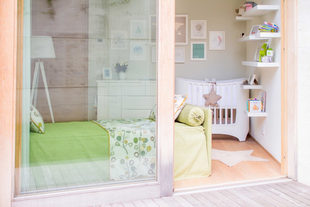 Immagine di una piccola cameretta per neonati neutra contemporanea con pareti bianche e parquet chiaro