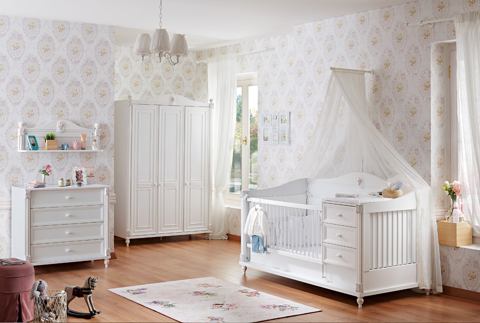 Réalisation d'une chambre de bébé minimaliste de taille moyenne avec un mur blanc, sol en stratifié et un sol marron.