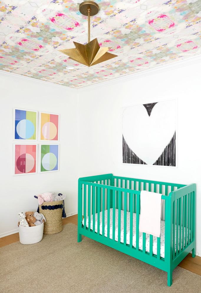 Cette image montre une chambre de bébé fille design avec un mur blanc, un sol en bois brun et un sol marron.