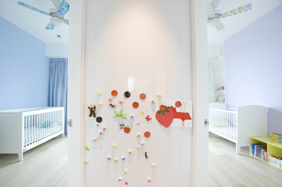 Modelo de habitación de bebé neutra contemporánea con suelo de madera clara y paredes azules