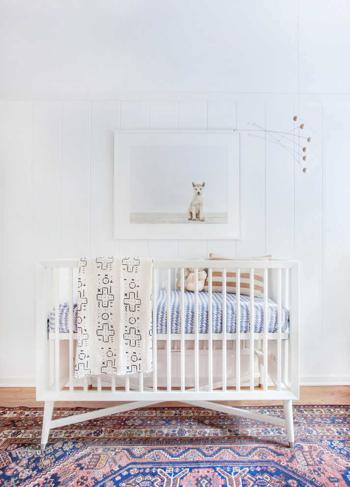 Cette photo montre une chambre de bébé neutre tendance avec un mur blanc.