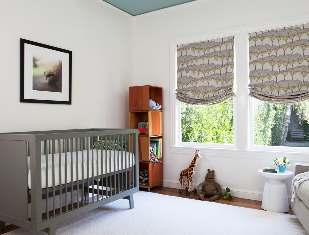 Réalisation d'une chambre de bébé neutre design de taille moyenne avec un mur blanc et un sol en bois brun.