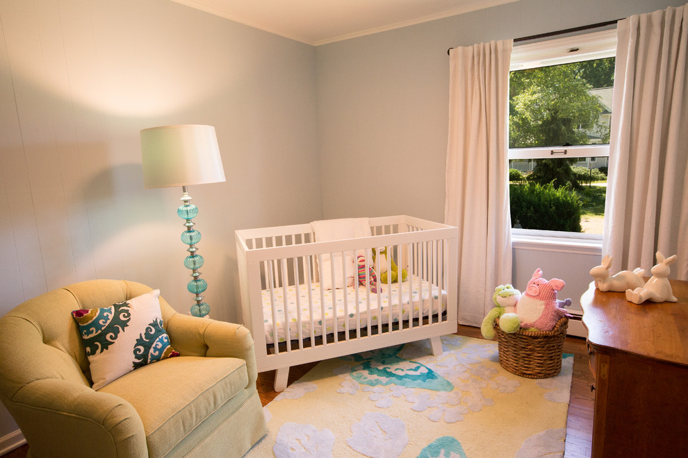 Idee per una cameretta per neonata moderna di medie dimensioni con pareti blu e pavimento in legno massello medio