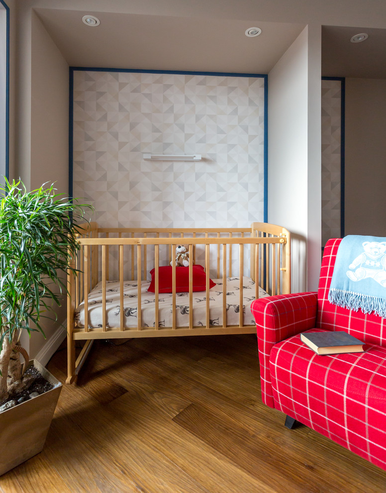 Стильный дизайн: нейтральная комната для малыша в современном стиле с серыми стенами, паркетным полом среднего тона и коричневым полом - последний тренд