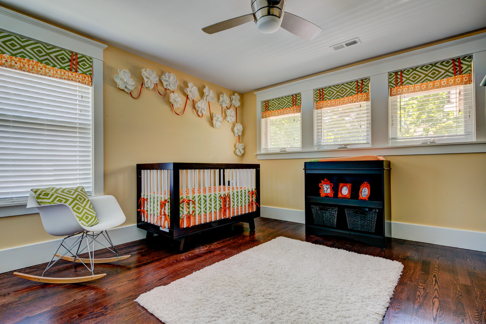 Cette photo montre une chambre de bébé neutre moderne de taille moyenne avec un mur orange et parquet foncé.