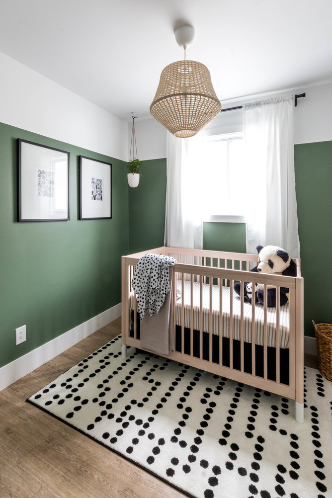 Diseño de habitación de bebé neutra minimalista pequeña con paredes verdes, suelo vinílico y suelo marrón