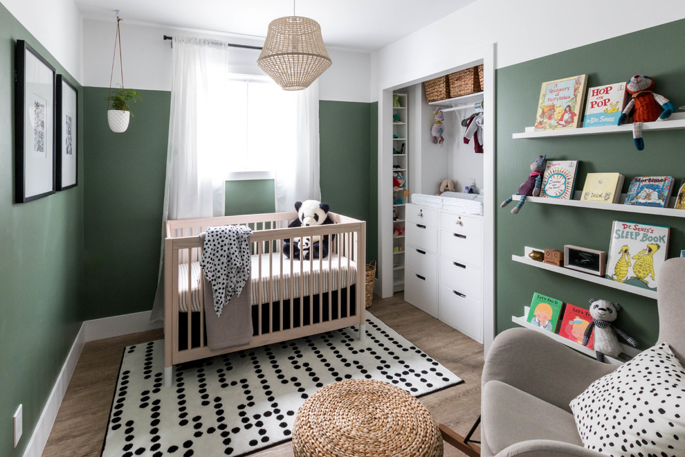 Diseño de habitación de bebé neutra moderna pequeña con paredes verdes, suelo vinílico y suelo marrón