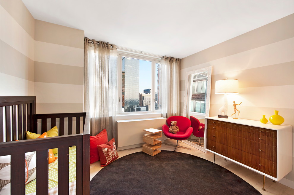 Diseño de habitación de bebé neutra actual de tamaño medio con paredes beige y suelo de madera clara