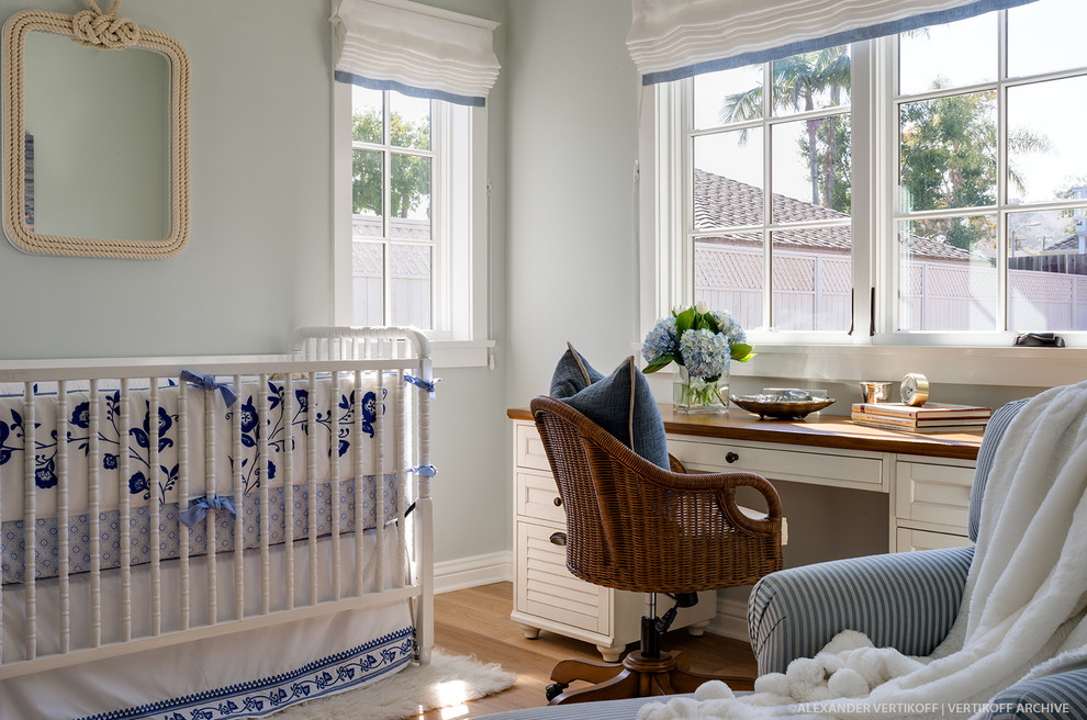 Design ideas for a small nautical nursery for boys in Santa Barbara with blue walls and light hardwood flooring.