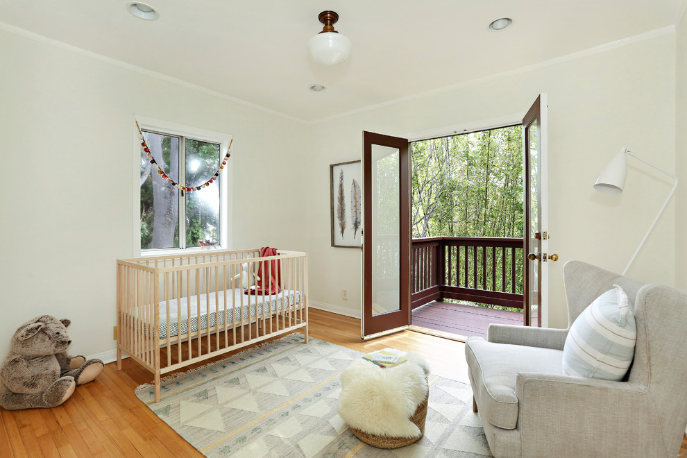 Classic gender neutral nursery in Los Angeles with beige walls, medium hardwood flooring and beige floors.