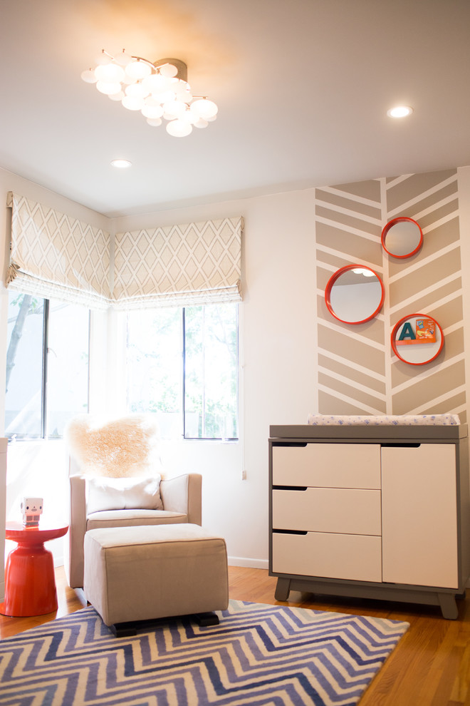 Immagine di una cameretta per neonato di medie dimensioni con pareti bianche e parquet chiaro