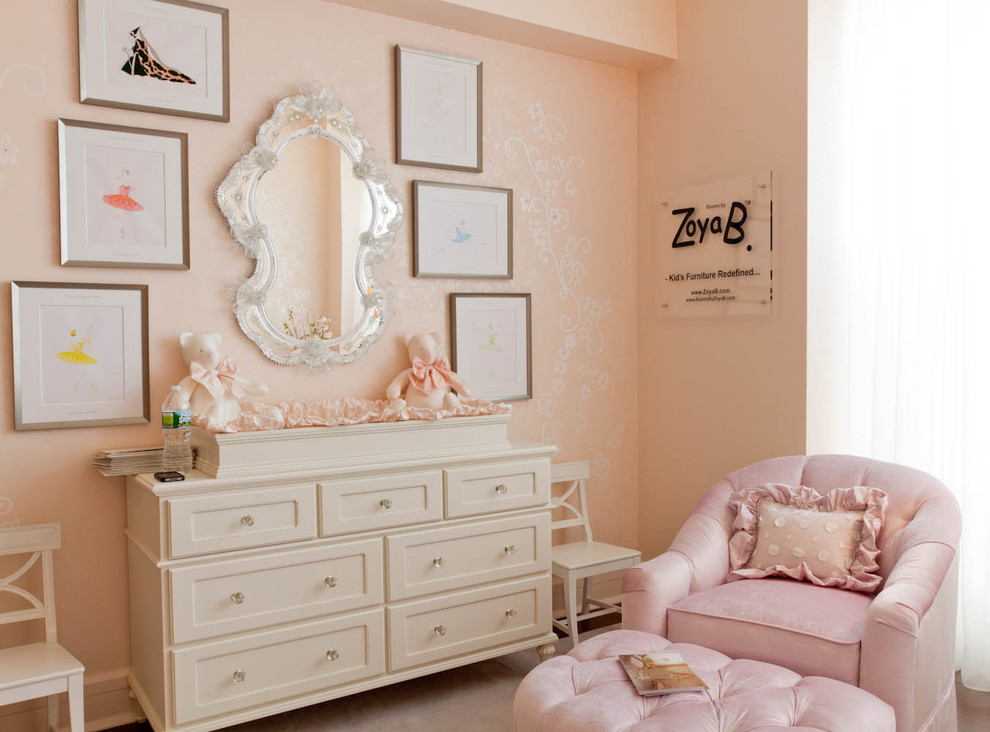 Example of a classic girl medium tone wood floor nursery design in New York with pink walls
