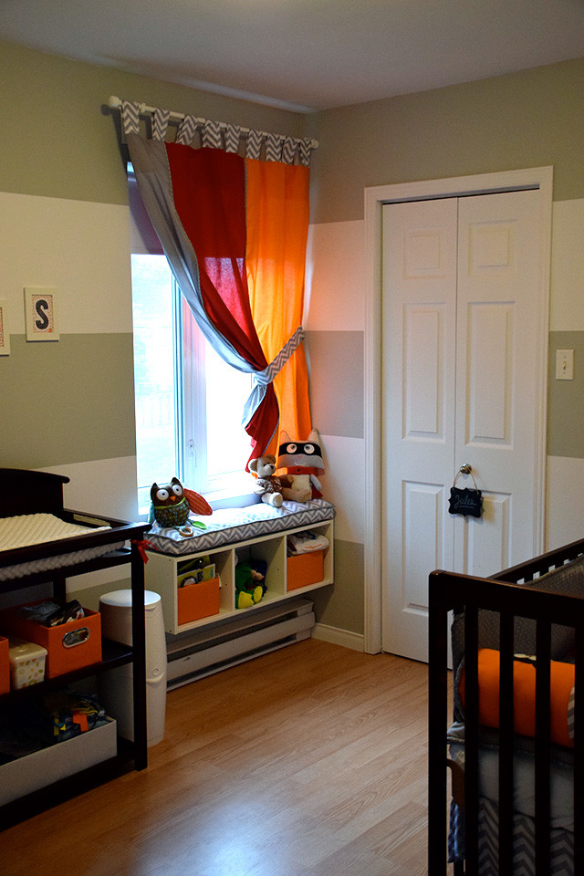 Ispirazione per una piccola cameretta per neonato minimalista con pareti grigie e pavimento in compensato