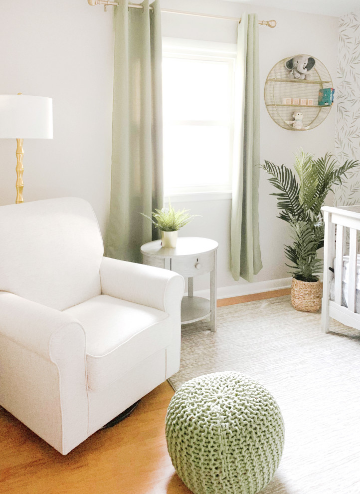 Modelo de habitación de bebé neutra clásica de tamaño medio con paredes beige, suelo de madera en tonos medios y suelo marrón