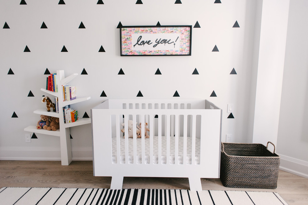 Aménagement d'une chambre de bébé neutre contemporaine de taille moyenne avec un mur gris, parquet clair et un sol marron.