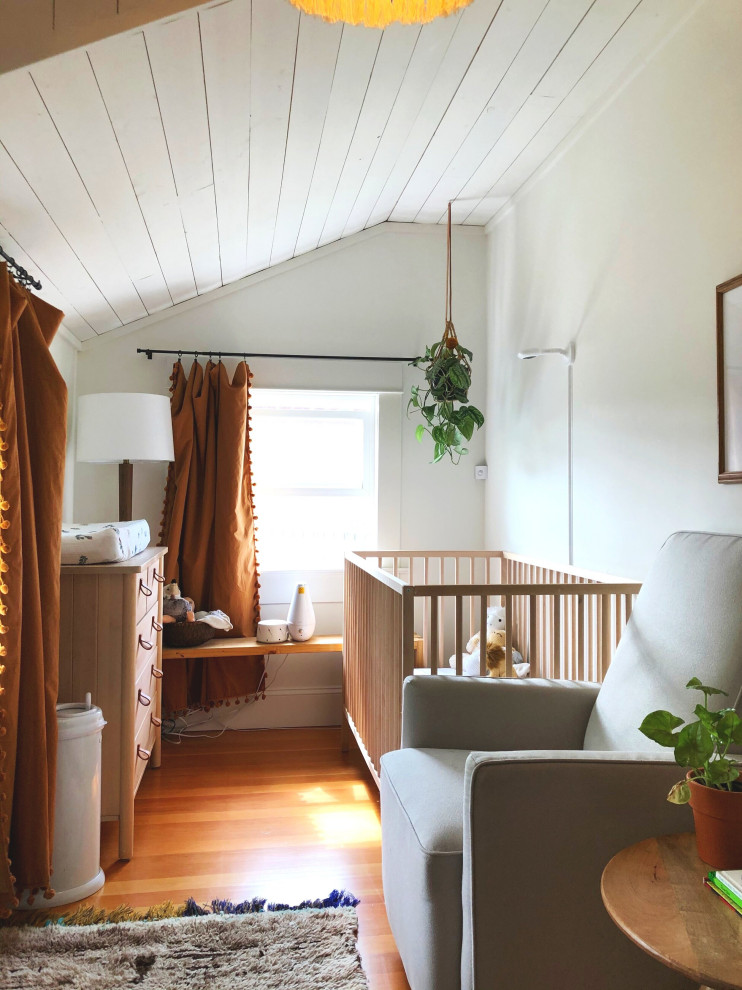 Inspiration for a small bohemian nursery for girls in Portland with white walls, medium hardwood flooring, brown floors and a timber clad ceiling.