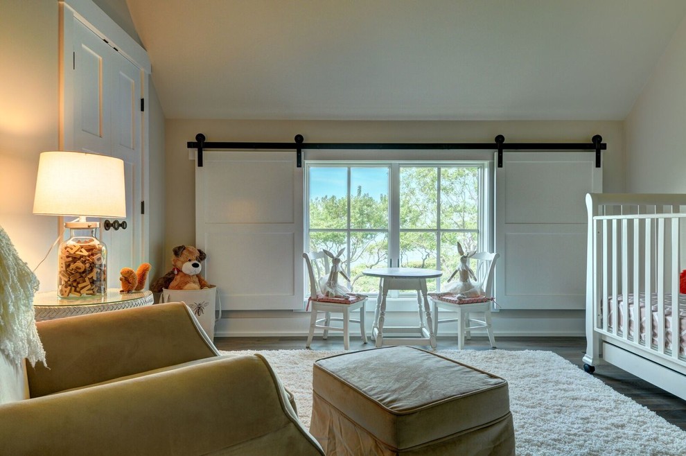Ejemplo de habitación de bebé neutra de estilo de casa de campo grande con paredes beige y suelo de madera clara