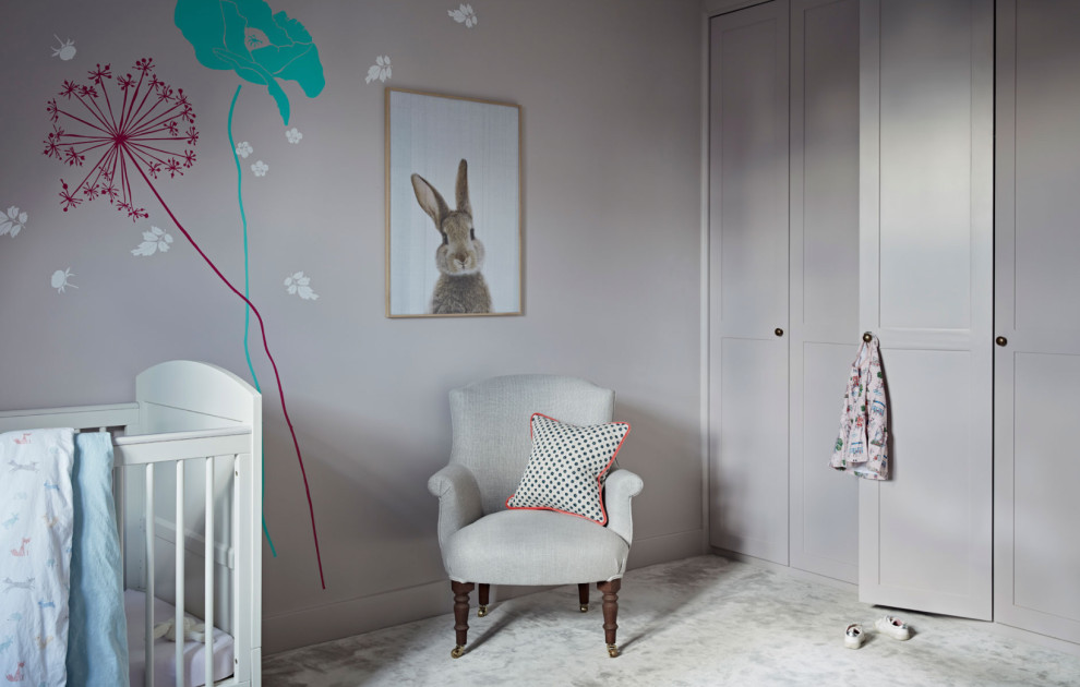 Mid-sized trendy girl carpeted and beige floor nursery photo in London with beige walls