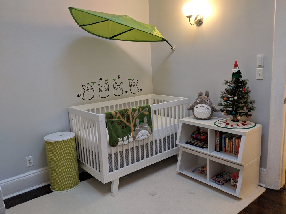 Aménagement d'une petite chambre de bébé moderne avec un mur gris et parquet foncé.