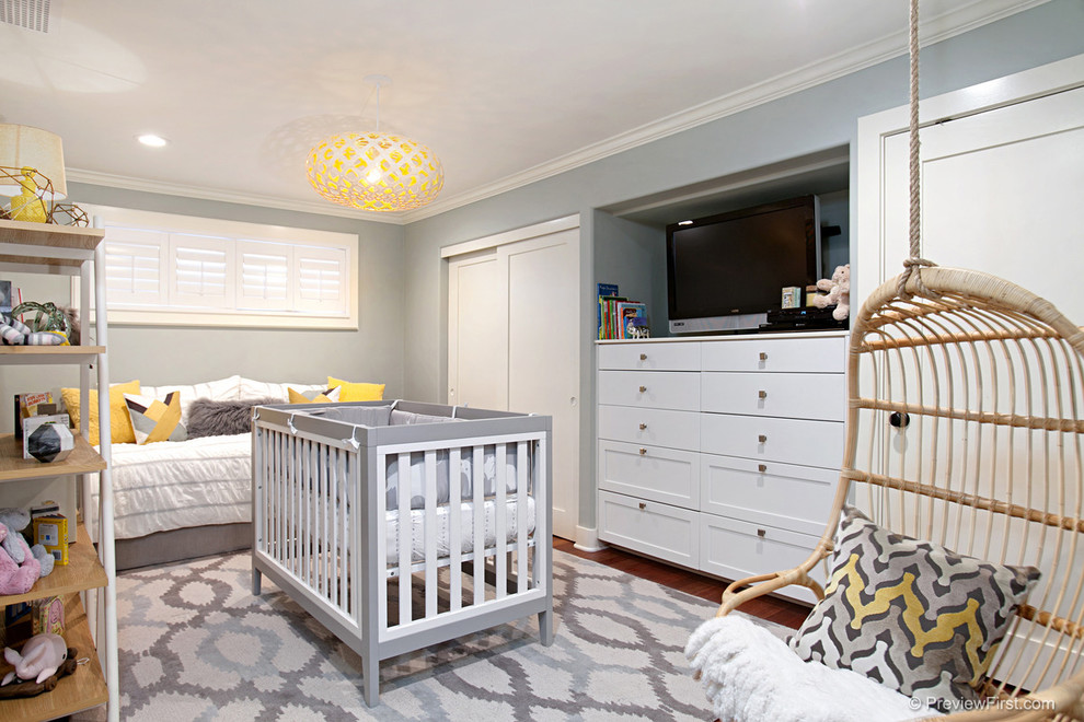 Modelo de habitación de bebé neutra clásica renovada de tamaño medio con paredes grises y suelo de madera en tonos medios