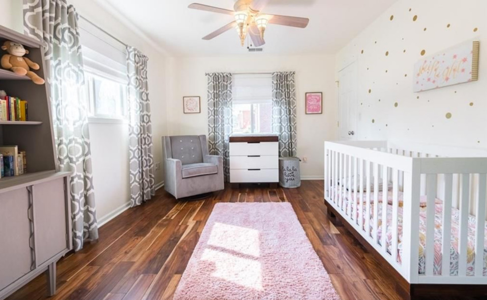 Foto de habitación de bebé niña minimalista grande con paredes blancas, suelo de madera en tonos medios y suelo marrón