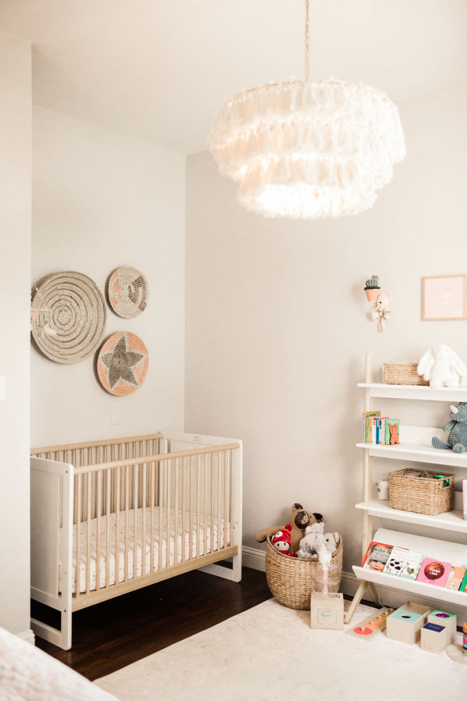 Cette photo montre une chambre de bébé fille nature de taille moyenne avec un mur gris, parquet foncé et un sol marron.