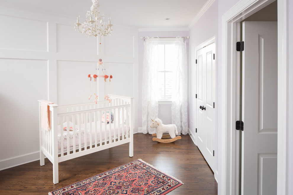 Traditional nursery for girls in Atlanta with purple walls, dark hardwood flooring and brown floors.