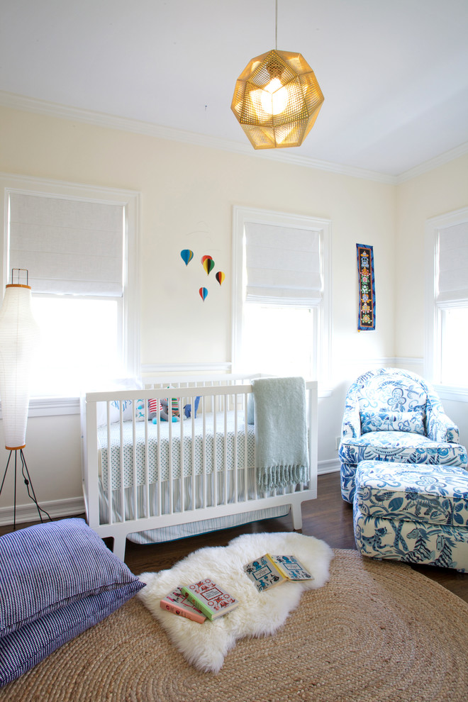 Réalisation d'une chambre de bébé neutre tradition avec un mur beige et parquet foncé.
