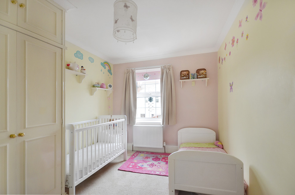 Пример оригинального дизайна: комната для малыша в классическом стиле с желтыми стенами, ковровым покрытием и серым полом для девочки